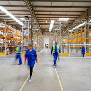 Staff walking a wide aisle in a distribution centre